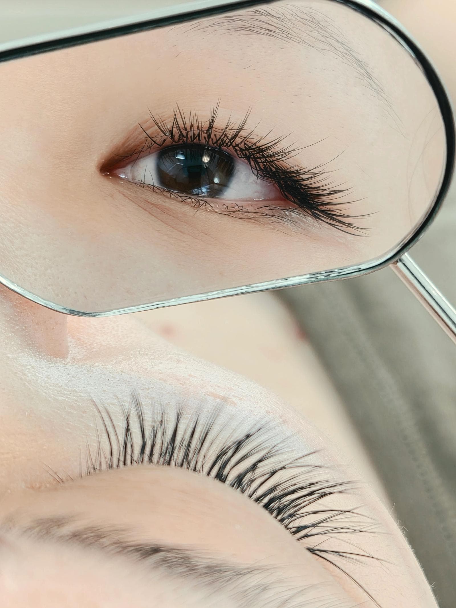 Close-up of a mirror reflecting a lash set, next to the client's eye